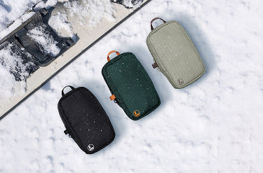 Translation missing: en.Black, hunter green, and mossy fog Leatherman tool pouches on a snowy background with a snowboard