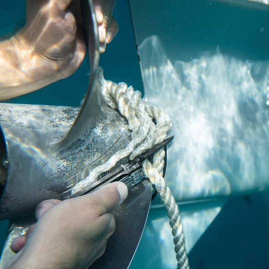Translation missing: en.Leatherman ARC cutting rope wrapped around boat propeller under water.