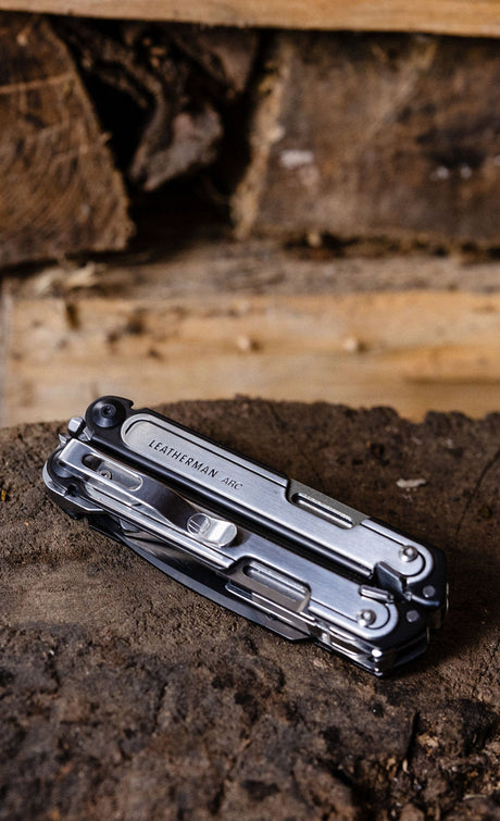 Translation missing: en.A Leatherman Arc closed laying on a piece of wood