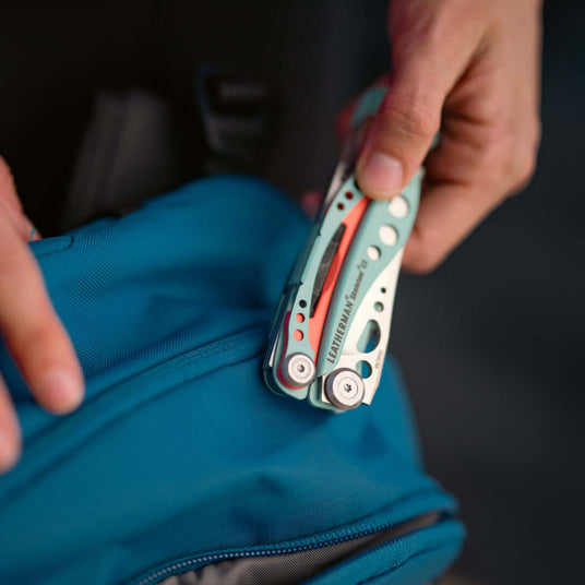 Translation missing: en.Person holding closed Skeletool CX over a backpack