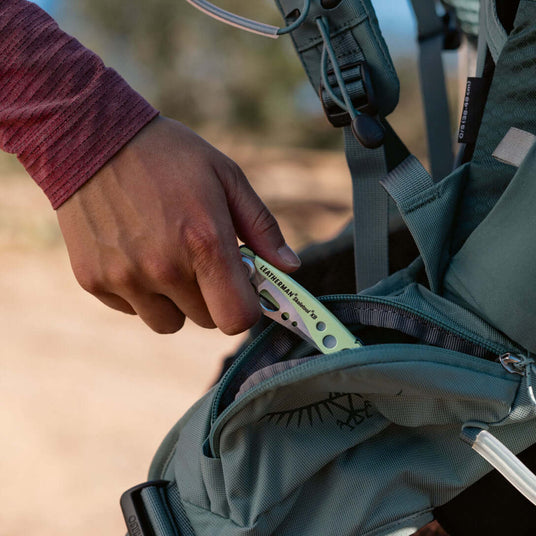 Translation missing: en.Person putting a closed Skeletool KB into a backpack