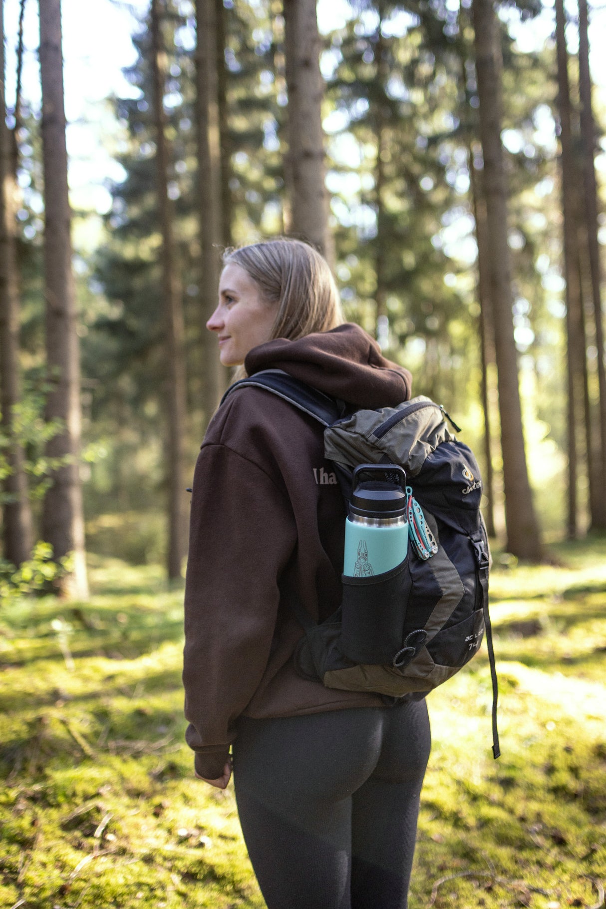 Translation missing: en.Hiker in a forest carrying a backpack with a mint green Yeti bottle in the side pocket