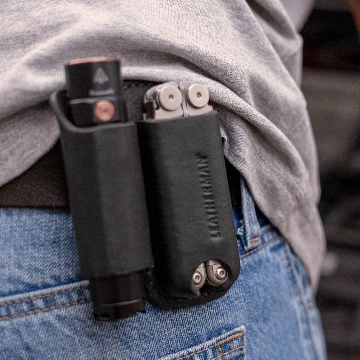 Translation missing: en.Black leather belt sheath holding a multitool and flashlight on a person’s hip