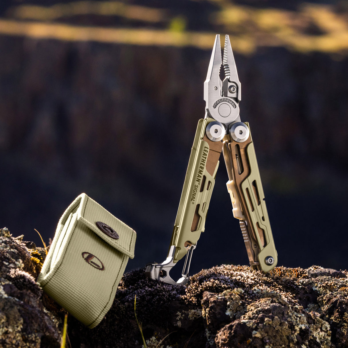 Translation missing: en.Sandstorm Leatherman Signal multitool with open pliers and matching case resting on rocky terrain outdoors