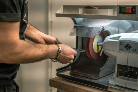 Translation missing: en.Technician sharpening a Leatherman multi-tool on a polishing wheel during the manufacturing process