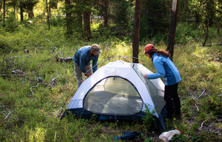 Couple setting up tent in the woods