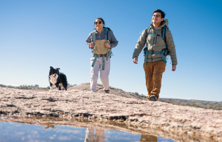 Couple and their dog hiking up a hill