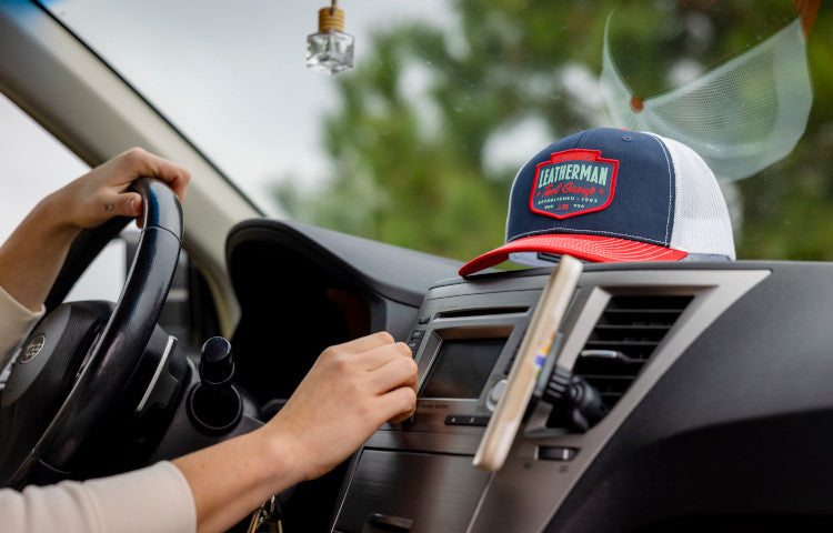 Translation missing: en.Person driving a car with a Leatherman Pacific Northwest Trucker hat on the dashboard
