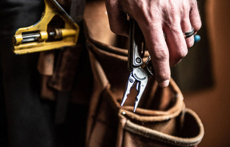 Person using a Leatherman tool to fix a wire fence.