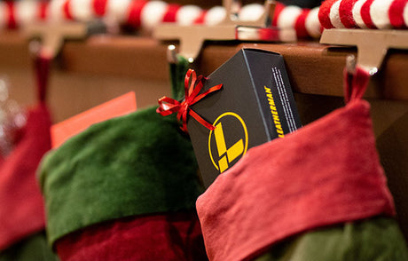 Leatherman box with a bow on it in a stocking hanging on a mantle.