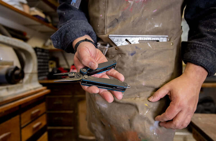 Translation missing: en.Person holding an older Leatherman multitool in a workshop, showcasing its features and design