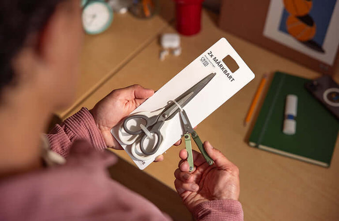 Translation missing: en.Person using the scissors on a Leatherman Micra in cardamom color to cut the zip ties on a package
