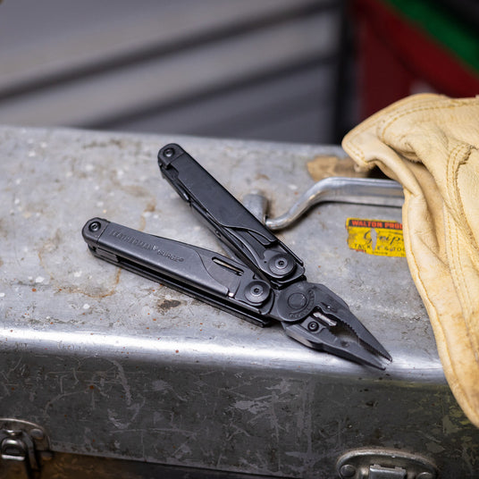 Translation missing: en.A black Leatherman Surge rests on a metal tool box, showcasing its compact design and versatility