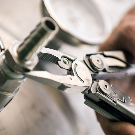 Translation missing: en.A person using a Leatherman Surge to tighten nut on bolt, demonstrating practical skills with tools in a hands-on setting