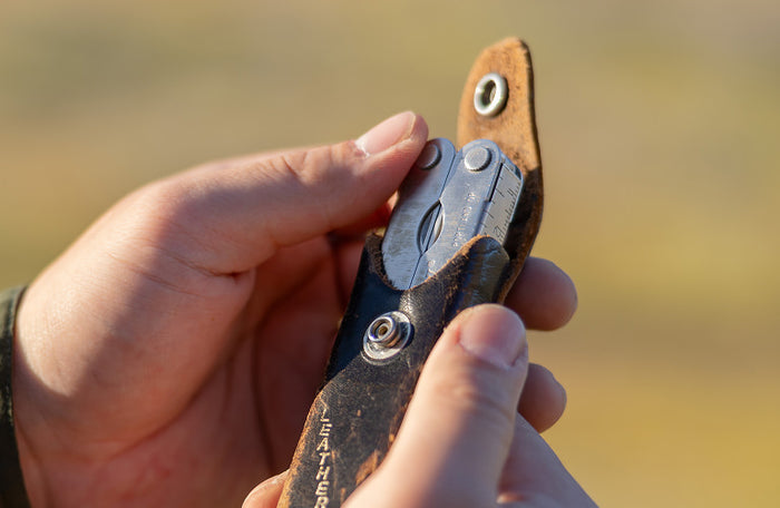 Translation missing: en.Person holding a Leatherman PST 2 multitool in a worn leather case outdoors