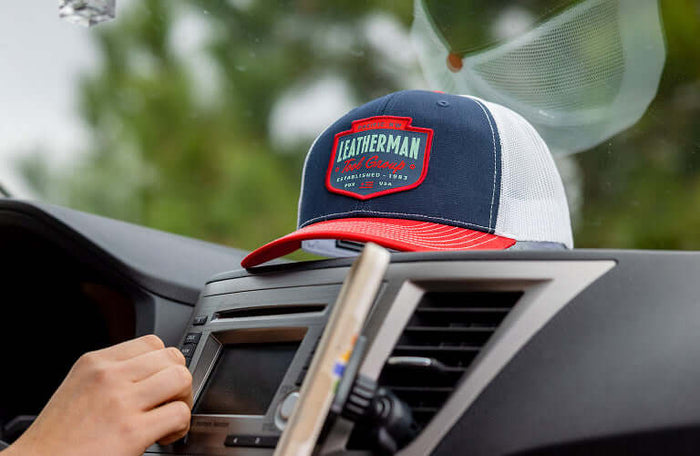 Translation missing: en.Leatherman Pacific Northwest hat resting on car dashboard, showcasing its stylish design and vibrant colors against a blurred natural background