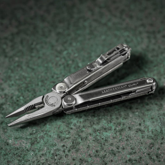 A Leatherman Curl laying on a tabletop with pliers and pocket clip showing.