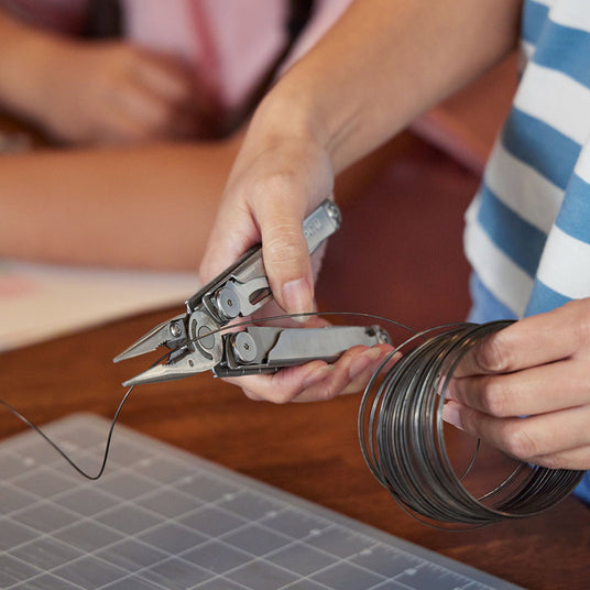 Someone using a Leatherman Wave+ wire cutter to cut a piece of wire.