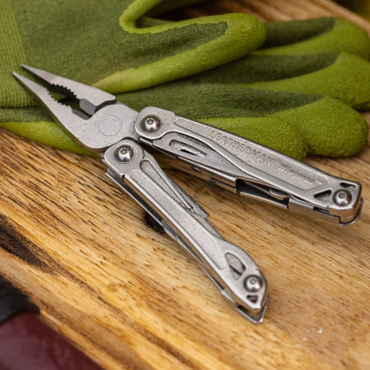 Wingman open laying on a table with pliers leaning on a pair of garden gloves