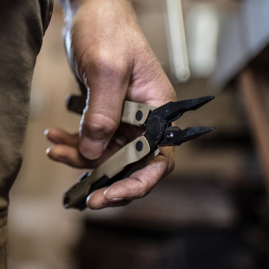 Translation missing: en.A hand holding a Leatherman Coyote Tan Rebar® multi-tool with pliers, showcasing its versatile design for various tasks