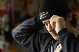 Translation missing: en.A person adjusting a black Leatherman Vintage Beanie while indoors, with the gold embroidered Leatherman logo visible on the front patch