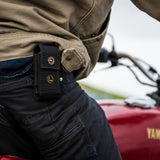 Translation missing: en.A man riding a motorcycle, wearing the Leatherman Black Bronze Nylon Sheath on his side, cruising down a scenic road