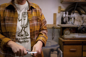 Translation missing: en.A person wearing a natural-colored Leatherman Mr. Wave Tee with a cartoon multitool design using a Leatherman multitool to sharpen a pencil