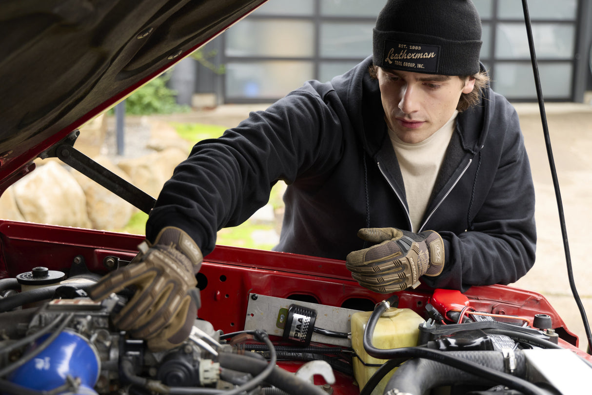 Translation missing: en.A person wearing a black Leatherman Vintage Beanie working under the hood of a red vehicle
