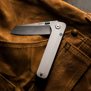 Translation missing: en.Leatherman Glider knife lies atop of brown Demin apron, creating a striking contrast between the tool and the fabric