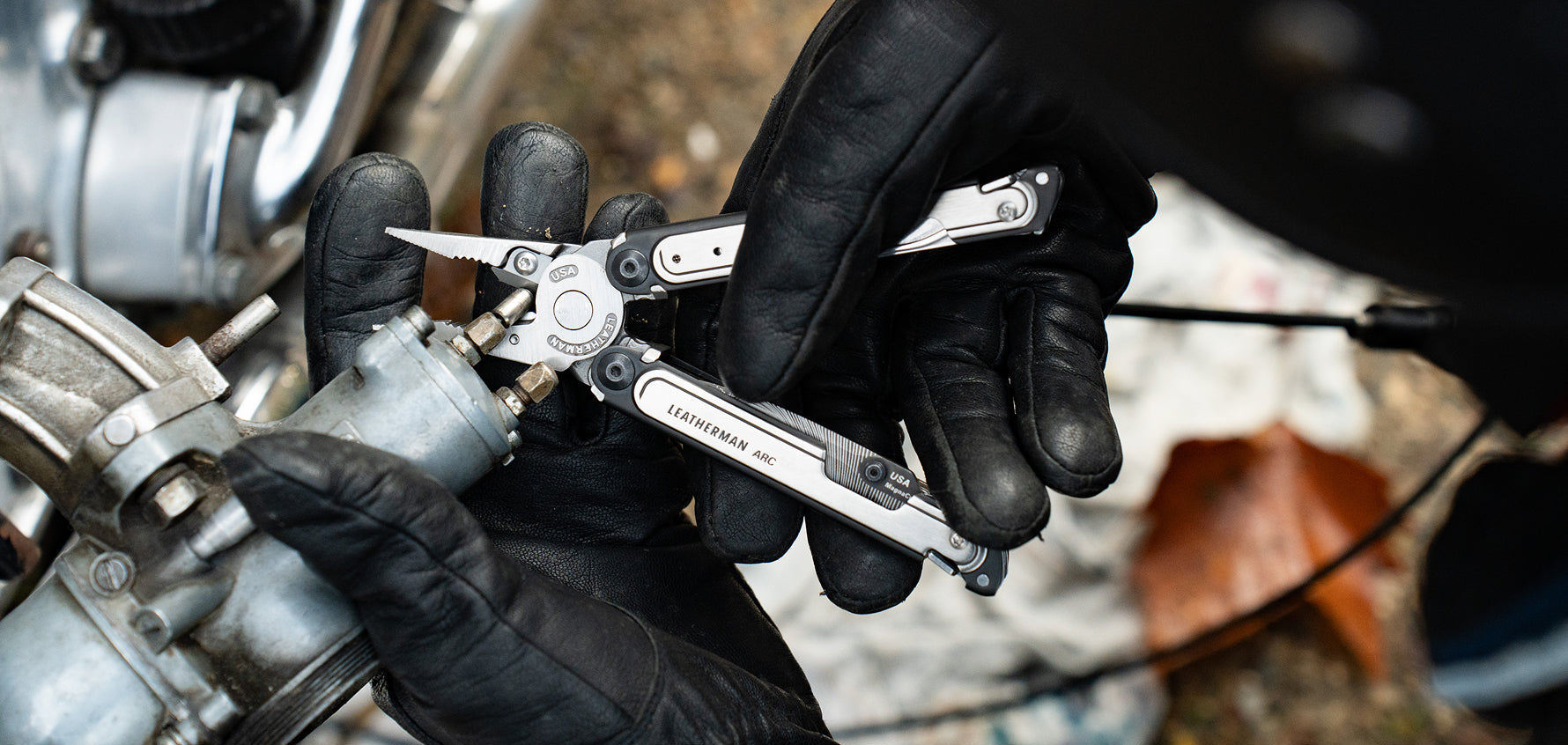 Leatherman ARC® multi‑tool, shown open with pliers being used on a motorcycle component.