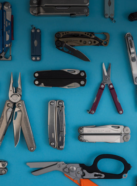 An array of Leatherman tools opened and closed laying on a blue background