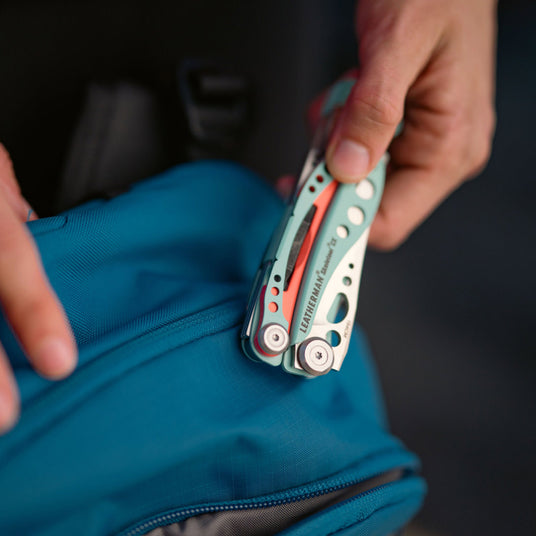 Person holding closed Skeletool CX over a backpack