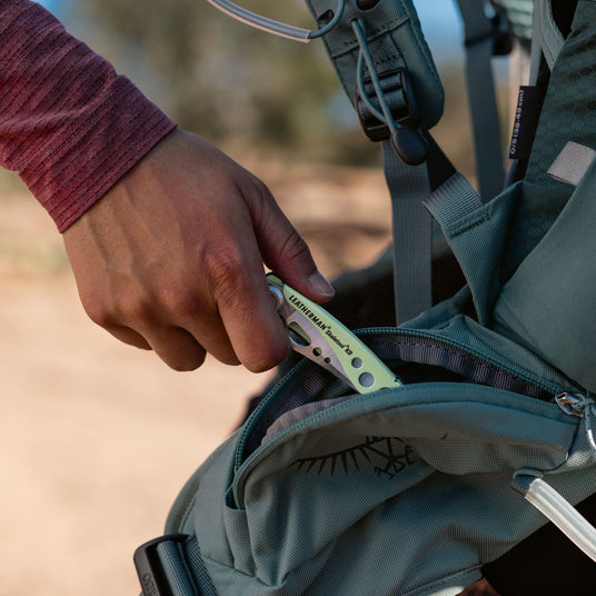 Person putting a closed Skeletool KB into a backpack