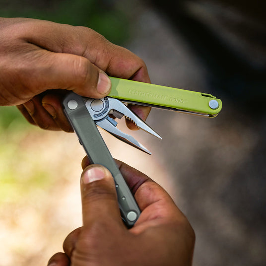 Translation missing: en.A close-up of hands holding the Mossy Slate Leatherman Bond® multitool, showcasing its sleek design and functionality