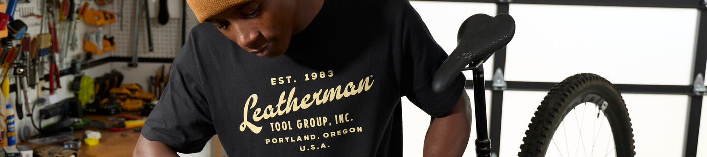 Translation missing: en.Man wearing a black t-shirt with 'Leatherman' branding in a workshop setting