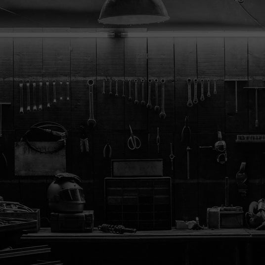 A dimly lit workshop with various tools hanging on the wall, a workbench, and storage drawers.