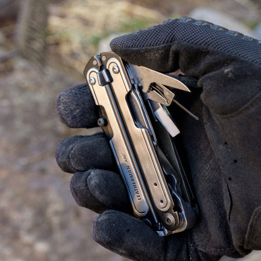 Person wearing black leather gloves holding Leatherman Arc. 