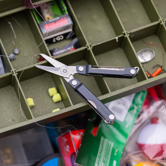 Opened Leatherman Micra on top of green fishing box. 