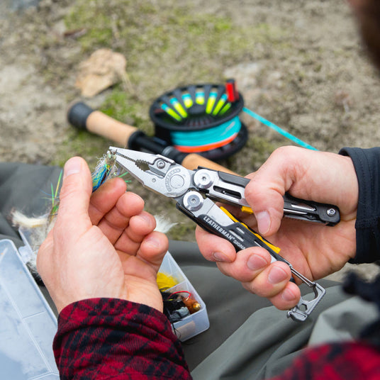 Person using Leatherman Signal pliers to hold a fishing hook.