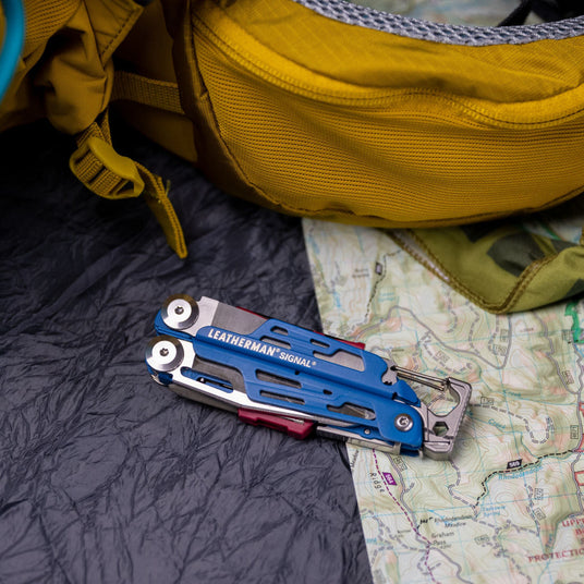 Closed Leatherman cobalt Signal on top of map next to yellow backpack. 