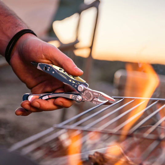 Man using Skeletool CX pliers to move a hot grill rack