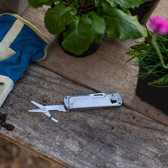 FREE T4 with scissors showing laying on a table outside next to plants and a glove