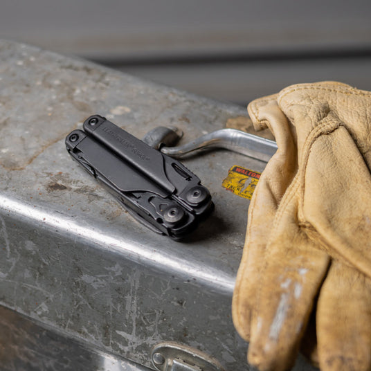 Closed black Leatherman Wave+ next to yellow safety glove. 