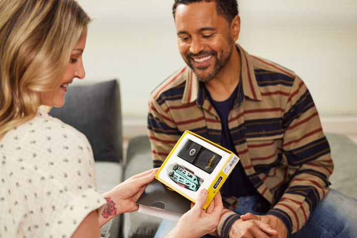 Translation missing: en.A man and woman sit on a couch, joyfully opening a Leatherman Signal gift together