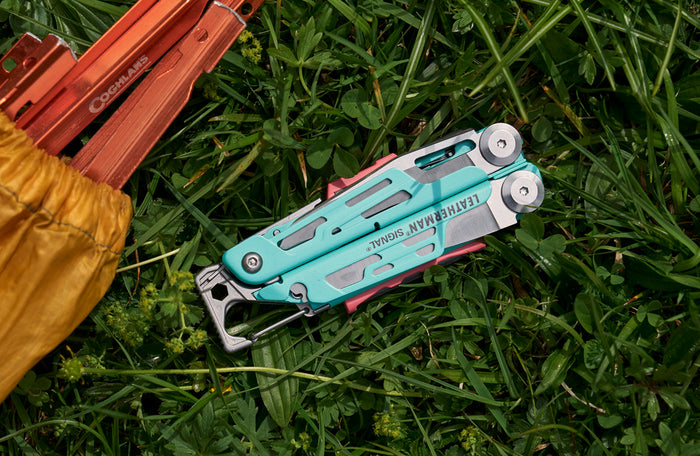 Translation missing: en.Aqua Leatherman Signal® multi-tool resting on lush green grass, showcasing its vibrant color and design