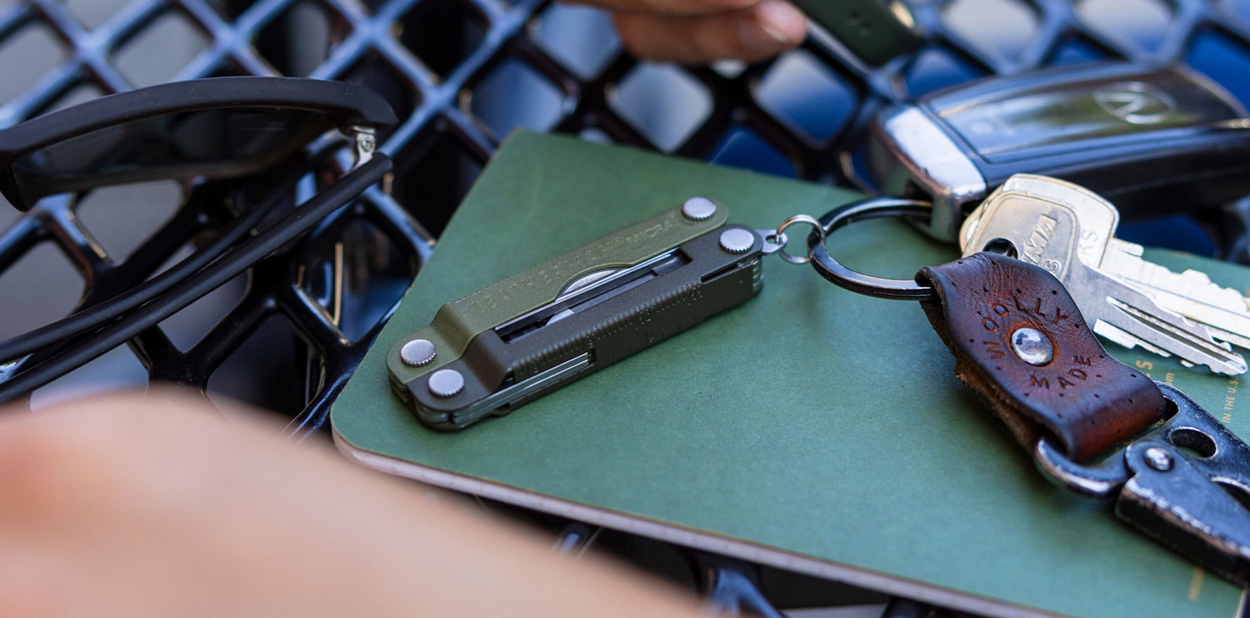 Leatherman Micra multi-tool in spruce color attached to keys laying on a green notebook.