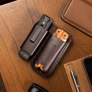 Translation missing: en.Dark Brown Premium Leather Sheath holding a black flashlight and orange multitool on a wooden desk