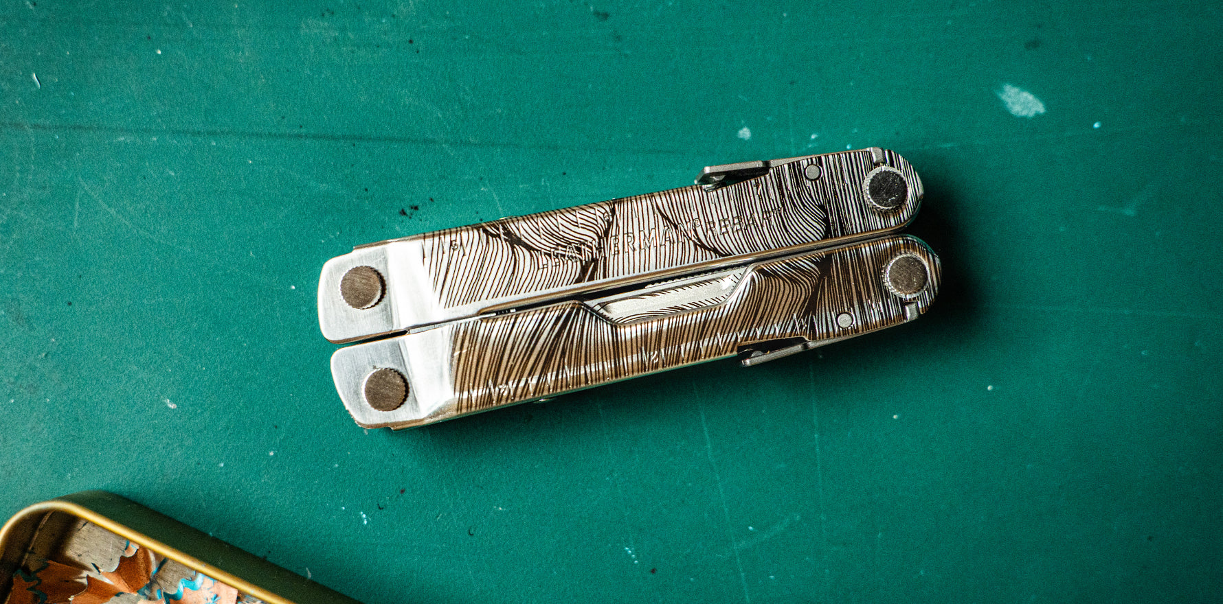 Leatherman Rebar® multi‑tool closed on a green work surface, showing engraved handles.