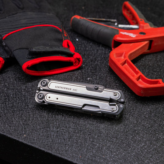 A close-up of Leatherman Arc, gloves, and a tool, highlighting essential equipment for various repair and maintenance tasks.