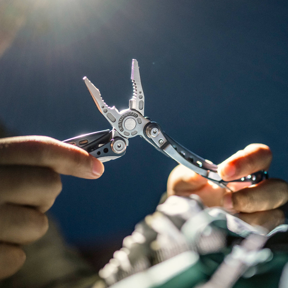 Translation missing: en.Hands holding an open Nightshade Leatherman Skeletool CX multitool pliers under bright light